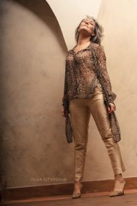 Grey hair model Valeria Sechi wearing a leopard print shirt and golden trousers