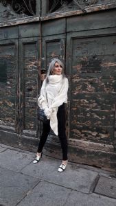 Grey hair model Valeria Sechi wearing a white wool sweater and gloves