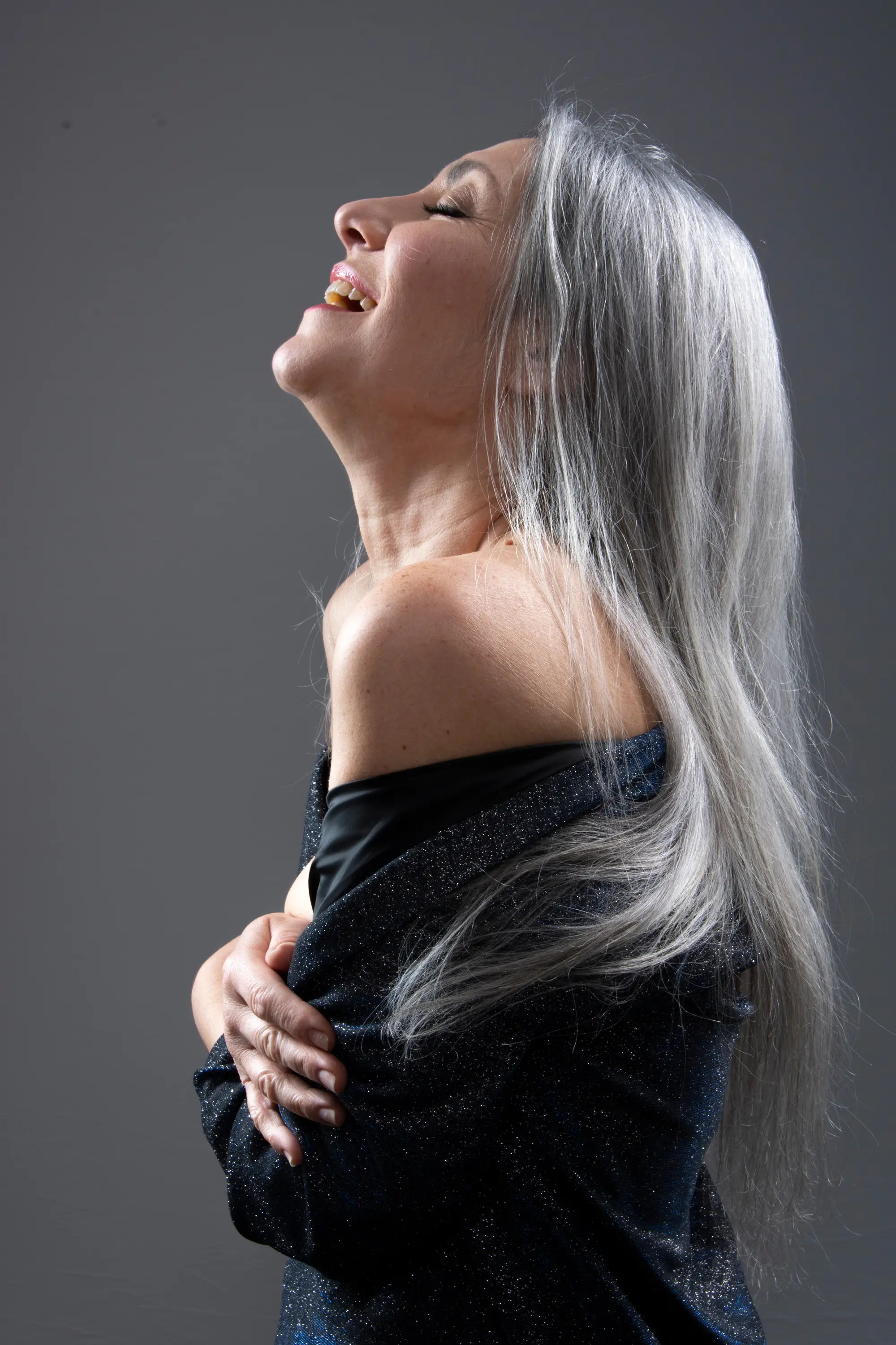 Valeria Sechi di profilo con i lunghi capelli grigio naturale che cadono fluenti — scatto signature per campagne haircare
