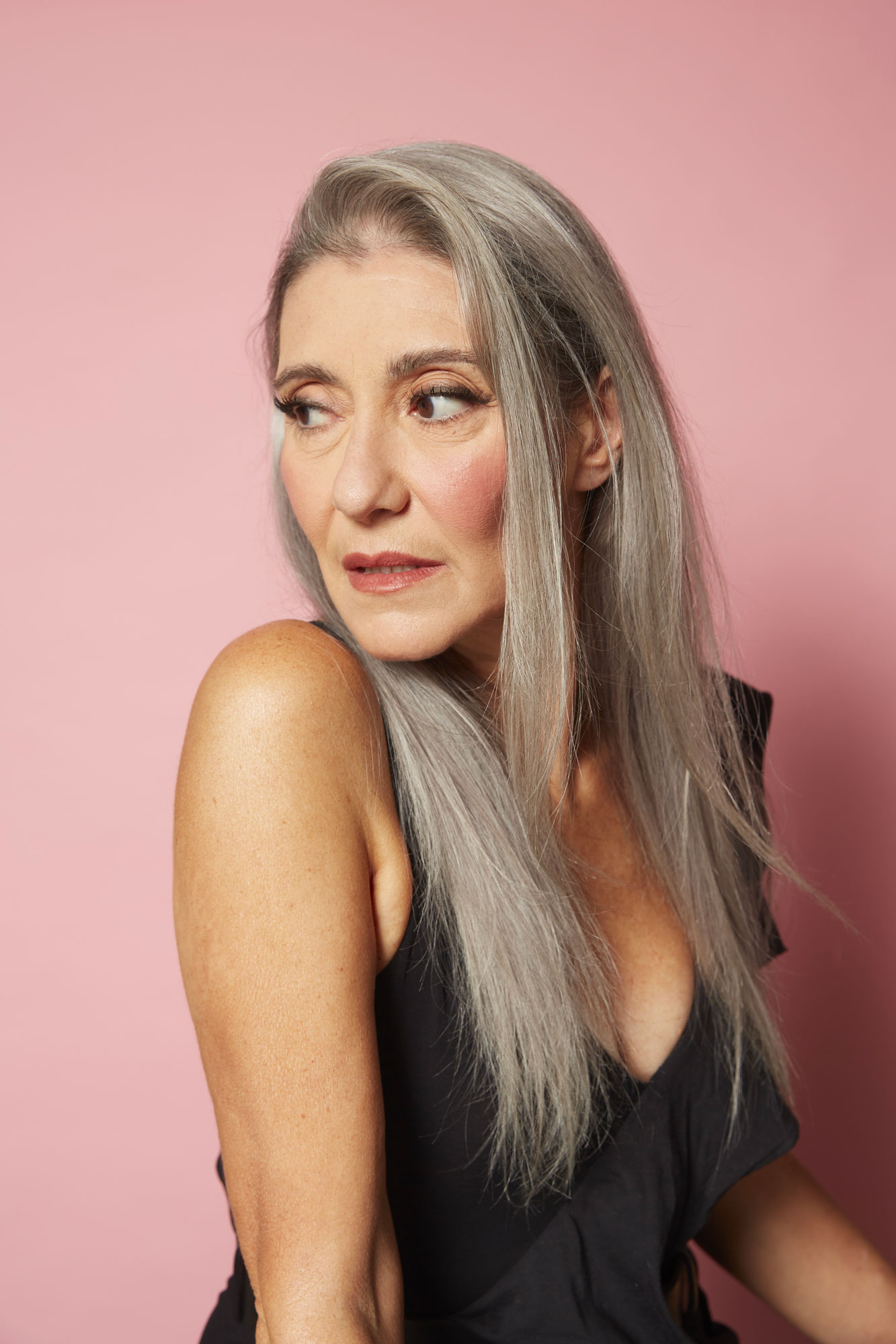 Mezzo busto di Valeria Sechi su fondale rosa con abito nero e capelli lunghi sciolti