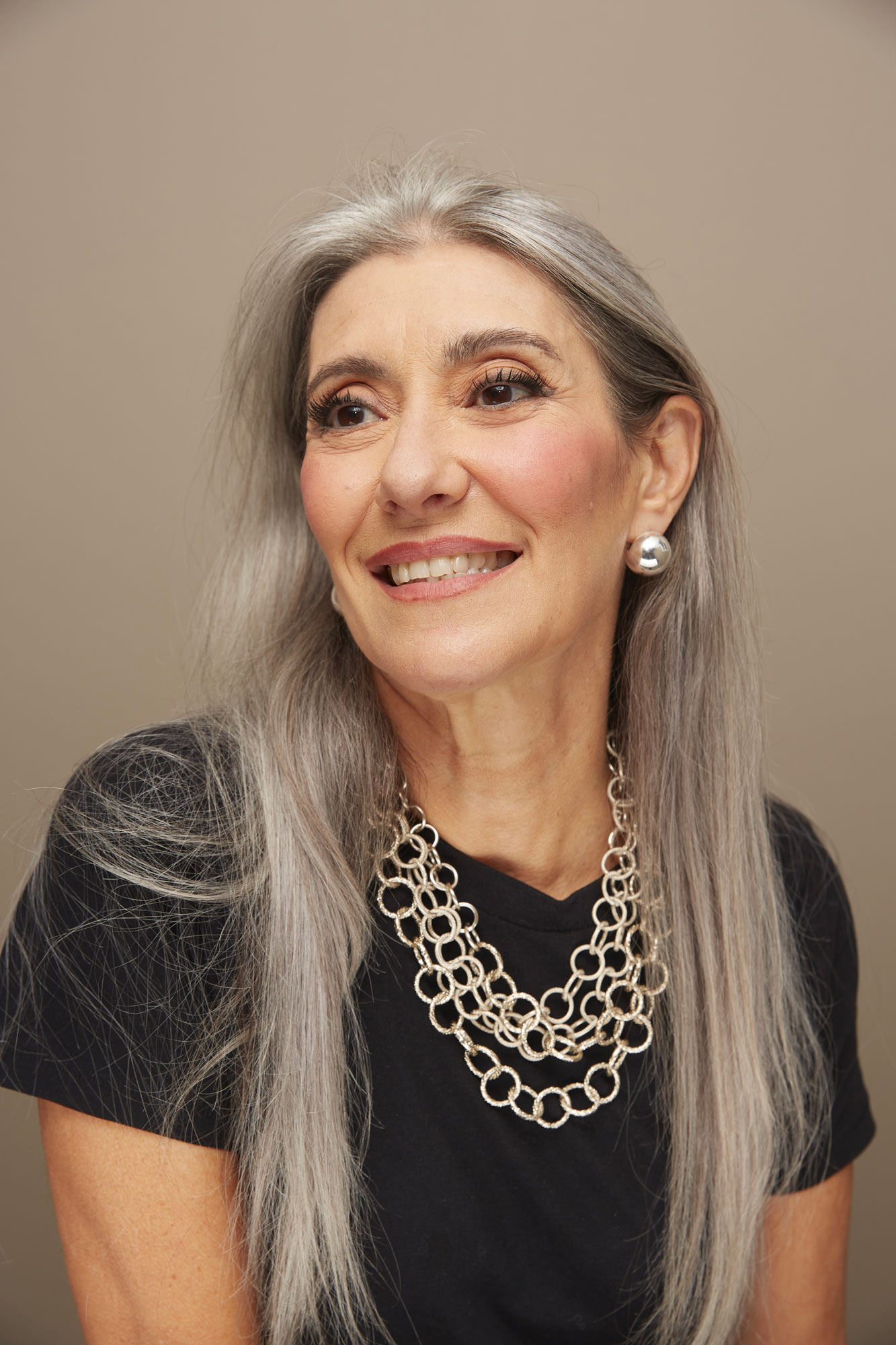 Mezzo busto di Valeria Sechi su fondale beige con abito nero e capelli lunghi sciolti