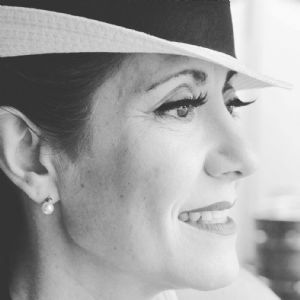 A black and white portrait of grey hair model Valeria Sechi with a white hat