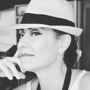 A black and white portrait of grey hair model Valeria Sechi with a white hat