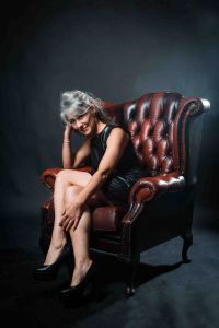 A portrait of grey hair model Valeria Sechi sitting on a leather armchair
