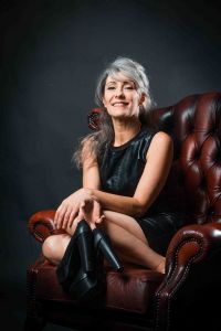 A portrait of grey hair model Valeria Sechi sitting on a leather armchair