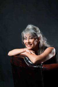 A portrait of grey hair model Valeria Sechi sitting on a leather armchair