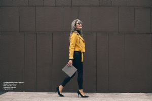 Grey hair model Valeria Sechi walking with yellow jacket and black trousers