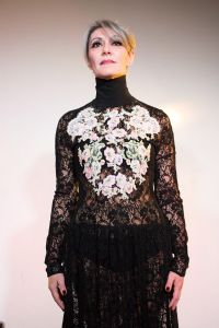 Grey hair model Valeria Sechi wearing a dress with floral embroidery
