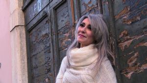 Grey hair model Valeria Sechi wearing a white wool sweater and gloves
