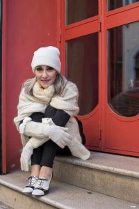 Grey hair model Valeria Sechi wearing a white wool sweater and gloves