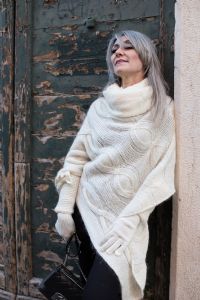 Grey hair model Valeria Sechi wearing a white wool sweater and gloves