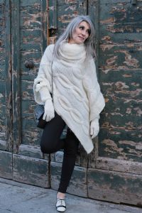 Grey hair model Valeria Sechi wearing a white wool sweater and gloves