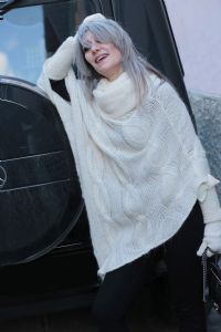 Grey hair model Valeria Sechi wearing a white wool sweater and gloves