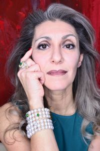 Grey hair model Valeria Sechi wearing an emerald ring and bracelet with pearls