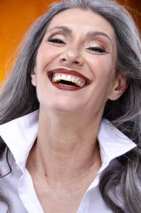 Italian grey hair model Valeria Sechi with a white shirt on an orange background