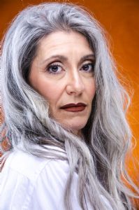 Italian grey hair model Valeria Sechi with a white shirt on an orange background
